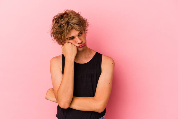 Young caucasian man with make up isolated on pink background who feels sad and pensive, looking at copy space. - Photo, image