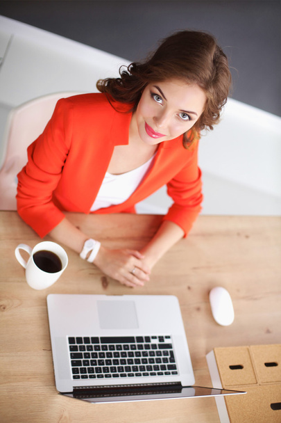 Attractive woman sitting at desk in office, working with laptop - Foto, afbeelding