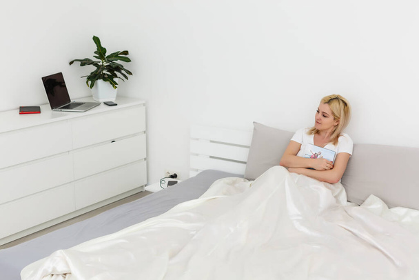 Gyengéd aranyos fiatal nő hosszú fehér haj fekszik és pihen az ágyban - Fotó, kép