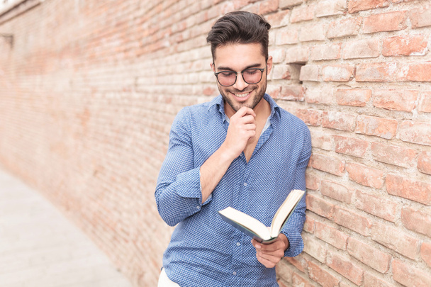 χαμογελαστός και στοχαστικός άνθρωπος casual διαβάζοντας ένα βιβλίο  - Φωτογραφία, εικόνα