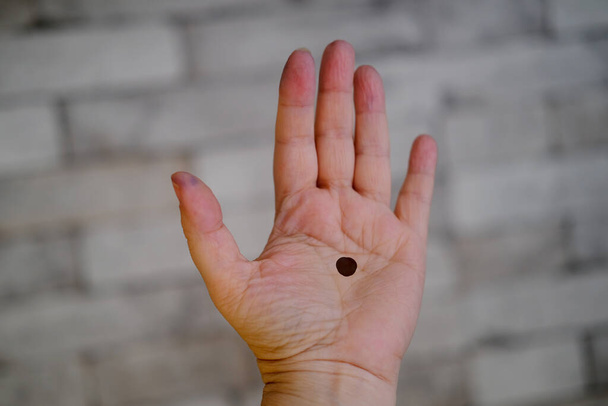 Nahaufnahme einer weiblichen Hand, ein schwarzer Punkt wird auf die offene Handfläche gezeichnet, das Konzept häuslicher Gewalt, Gefangenschaft und Knechtschaft, Entführung, Hilfeersuchen - Foto, Bild