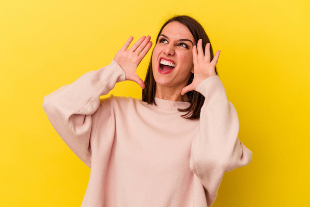 Young caucasian woman isolated on yellow background shouting excited to front. - Fotó, kép