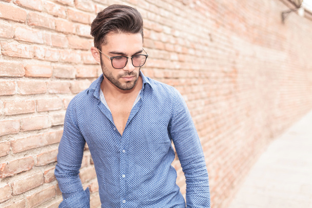 young casual man with glasses looks down - Foto, Imagem