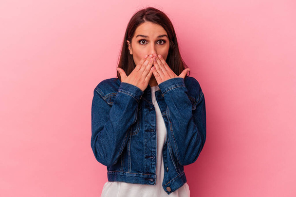Young caucasian woman isolated on pink background shocked covering mouth with hands. - Fotó, kép