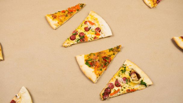 Four triangular slices of different types of pizza on a beige kraft paper background. Concept of a popular delicious food. - Photo, Image