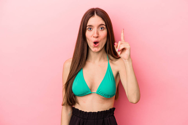 Young caucasian woman wearing bikini isolated on pink background having an idea, inspiration concept. - Photo, Image