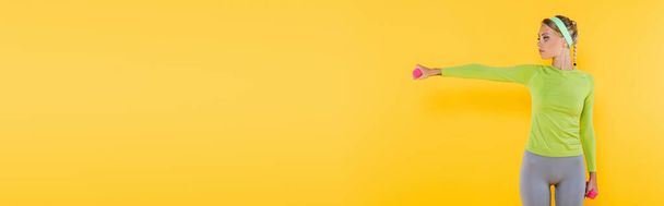 karcsú nő sportruházat képzés súlyzók elszigetelt sárga, banner - Fotó, kép