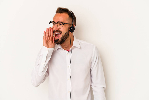 Young caucasian telemarketer man with tattoos isolated on white background  shouting and holding palm near opened mouth. - Fotó, kép