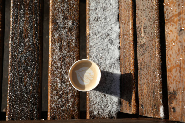 Cappuccino en una mesa de madera al aire libre, nieve, finales de otoño - Foto, imagen
