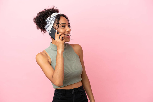 Jovem latina isolada no fundo rosa mantendo uma conversa com o celular - Foto, Imagem