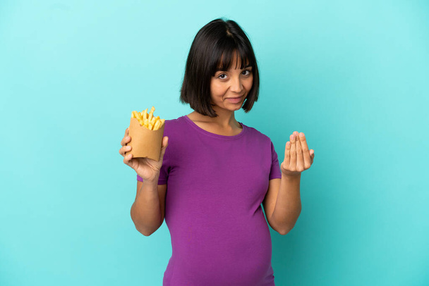 Femme enceinte tenant des frites sur fond isolé invitant à venir avec la main. Heureux que tu sois venu - Photo, image