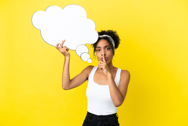 Young african american woman isolated on yellow background holding a thinking speech bubble and doing silence gesture - Photo, image