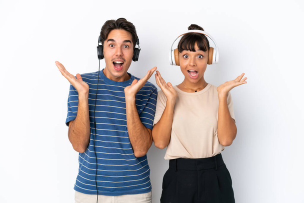 Young mixed race friends isolated on white background surprised and listening music - Φωτογραφία, εικόνα