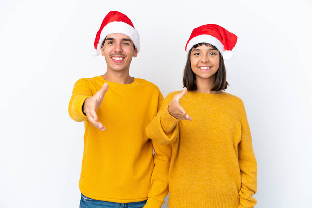 Jeune couple mixte célébrant Noël isolé sur fond blanc serrant la main pour conclure une bonne affaire - Photo, image