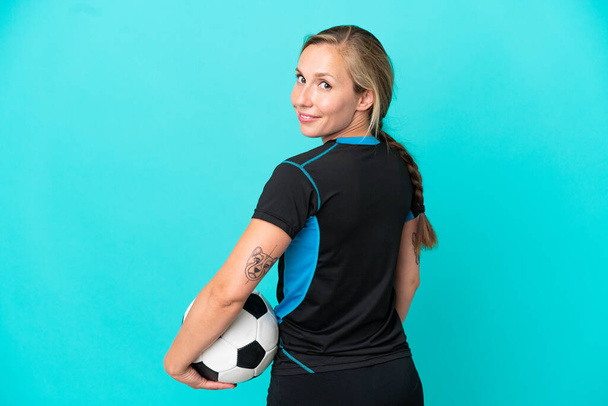Νεαρή Αγγλίδα γυναίκα απομονωμένη σε μπλε φόντο με μπάλα ποδοσφαίρου - Φωτογραφία, εικόνα