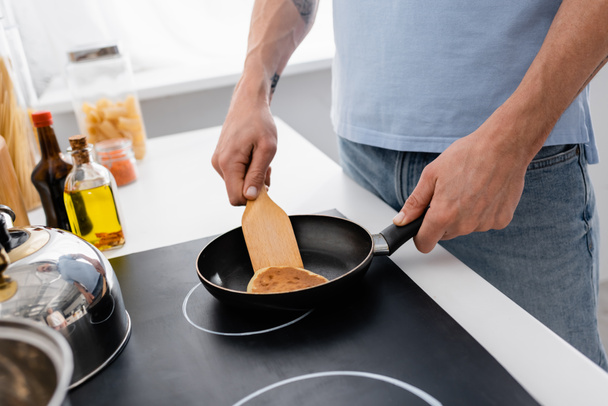 Cropped view of man with spatula cooking pancake in kitchen  - Foto, imagen