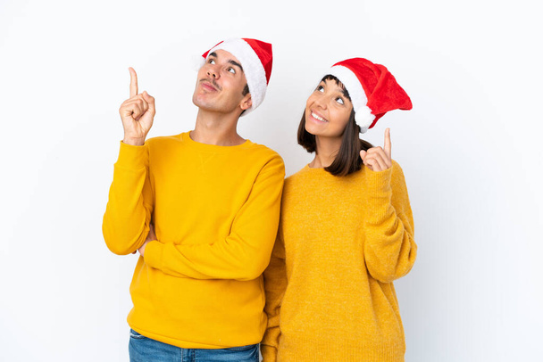 Junge gemischte Rasse Paar feiert Weihnachten isoliert auf weißem Hintergrund zeigt eine großartige Idee und Blick nach oben - Foto, Bild