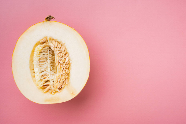 Mitad de melón melón conjunto, sobre fondo de verano texturizado rosa, vista superior plano, con espacio de copia para el texto - Foto, imagen