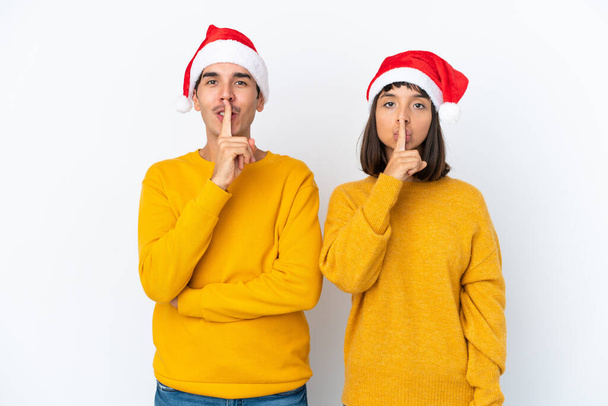 Giovane coppia mista che celebra il Natale isolato su sfondo bianco mostrando un segno di chiusura della bocca e silenzio gesto - Foto, immagini