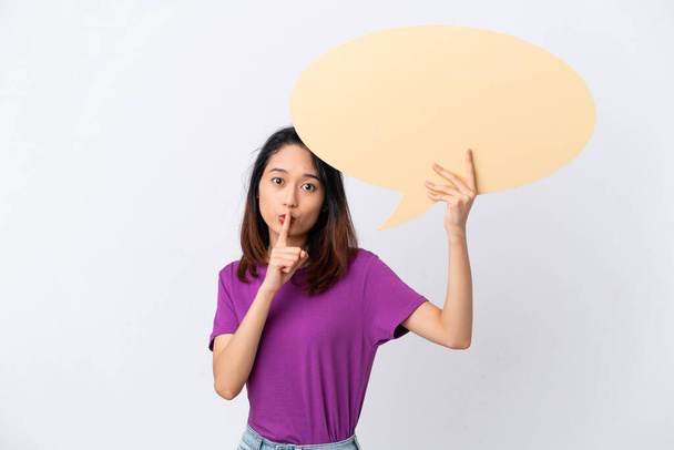 Young Vietnamese woman isolated on white background holding an empty speech bubble and doing silence gesture - Valokuva, kuva