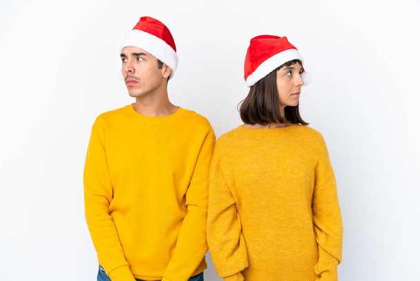 Junges gemischtes Paar feiert Weihnachten isoliert auf weißem Hintergrund nervös und verängstigt - Foto, Bild