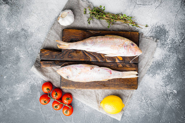 Raw red mullet or sultanka fresh whole fish set, with ingredients and herbs, on gray stone table background, top view flat lay, with copy space for text - Fotó, kép