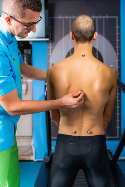 Colocación de marcadores en la espalda de los hombres para los análisis de marcha y caminar en 3D  - Foto, Imagen