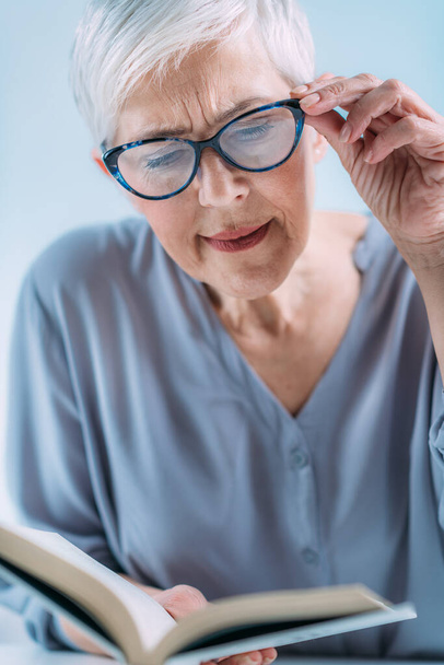 Glaucoma. Senior woman a reading book, having ocular tension.   - Фото, зображення