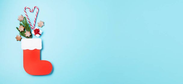 Saint-Nicolas - Botte rouge aux bonbons, biscuits épicés au gingembre et cadeaux pour le 6 Décembre sur fond bleu. Allemand, Pays-Bas, Belgique Consommation de Noël appelée Nikolaus, vue de dessus, espace de copie. - Photo, image