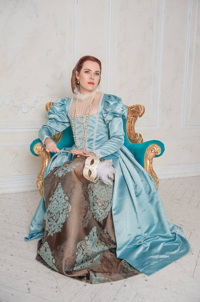 Hermosa mujer joven de estilo medieval vestido azul sentado en el armchai - Foto, imagen