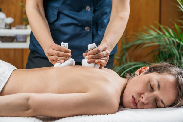 Kruidenzakje Massage bij Ayurvedic Wellness Center. vrouw liggend met ogen dicht genietend van de behandeling. - Foto, afbeelding