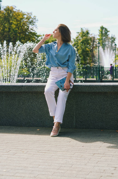 Urban portrait of young elegant business woman in eye glasses and casual clothes in city. Woman walking in green park, relaxing, smiling in sunny day. Hobby and leisure. - Fotografie, Obrázek