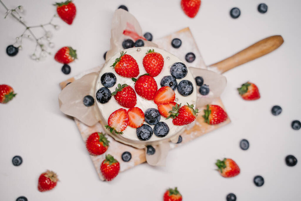 Confectionery on white background, strawberry blueberry cake - Фото, изображение