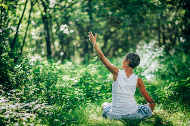 Collegamento con la Natura, Meditazione Mindfulness. Una donna memore che medita, circondata da una bellissima natura - Foto, immagini
