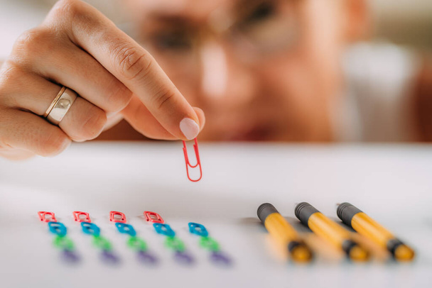 Woman with OCD  Obsessive compulsive disorder concept. Placing paperclips in a straight line.  - Photo, Image