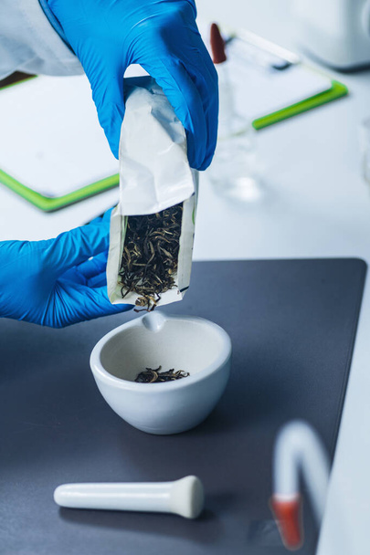 Bitki çayının kalite kontrolü, böcek ilacı testi. Laboratuvar teknisyeni laboratuarda çay örneği hazırlıyor. - Fotoğraf, Görsel