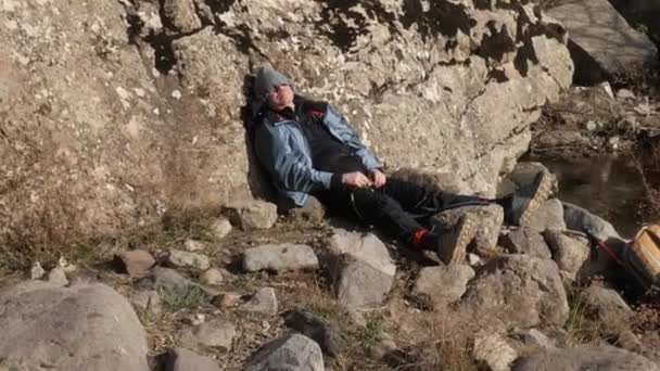 Un excursionista duerme apoyado en una roca. - Metraje, vídeo