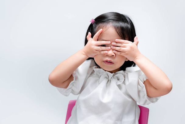 4 years child girl  over hands on her eyes. Kid playing peekaboo. On isolated white background. - Фото, изображение