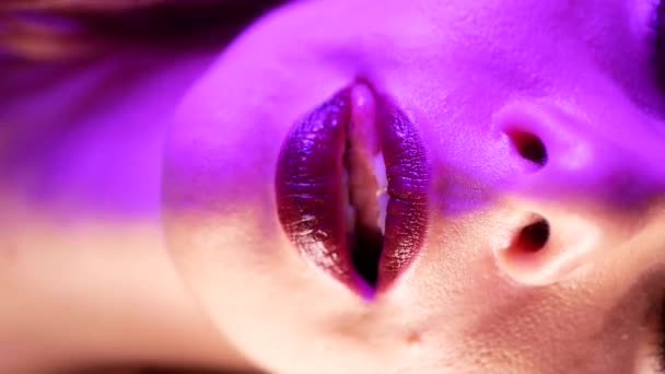 Donna sexy lecca le labbra. Luce incandescente al neon. Primo piano estremo. Concetto di vita notturna - Filmati, video