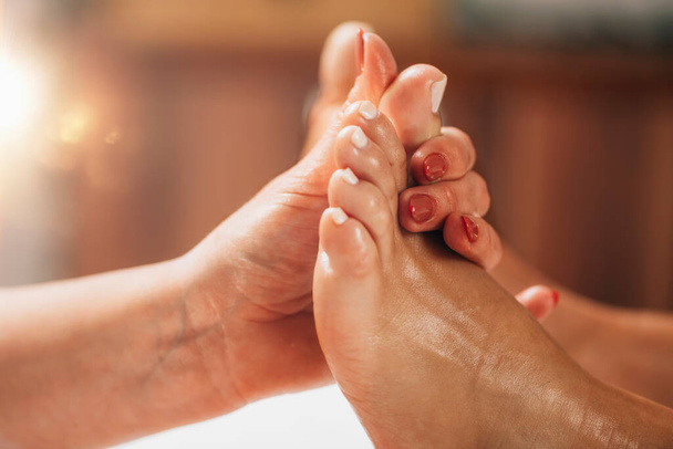 Reflexology Foot Massage. Reflexologist applying pressure to clients big toe at a wellness center  - Foto, imagen