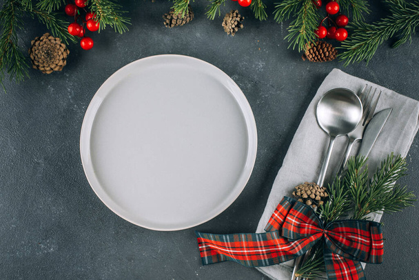 Накрытие праздничного стола на синий стол. Белая тарелка и серебряная посуда. Рождественское украшение. Концепция макета еды - Фото, изображение