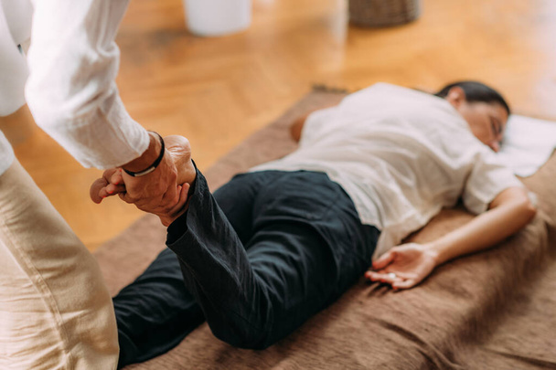 Terapista che allunga la gamba alle donne. Massaggio shiatsu  - Foto, immagini
