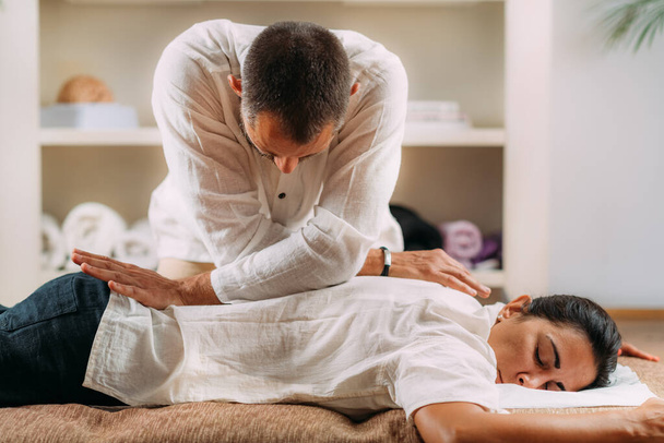 Терапевт массирует спину женщинам. Женщине делают массаж спины шиацу.  - Фото, изображение