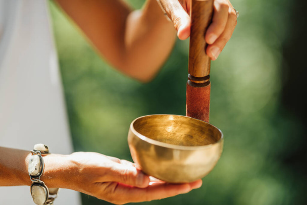 Hands holding Tibetan singing bowl outdoors, playing calming sounds - Photo, Image