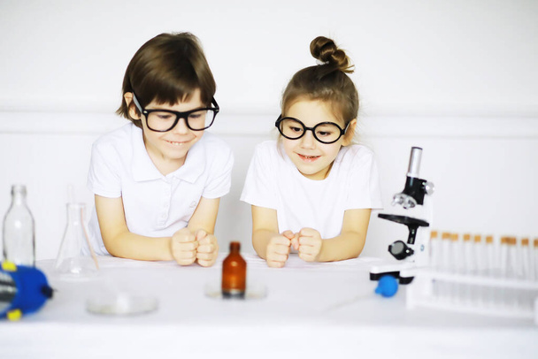 Двоє милих дітей на уроці хімії роблять експерименти ізольовані на білому фоні
 - Фото, зображення
