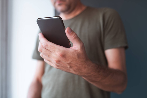 Man reading text message on mobile smart phone, selective focus on hand and device - Photo, image