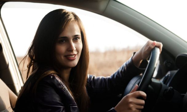 una joven hispana latina mirando curiosamente hacia adelante desde la ventana de su coche moderno. retrato de estilo de vida de una chica exitosa y feliz conduciendo. conducción y viaje en coche  - Foto, imagen
