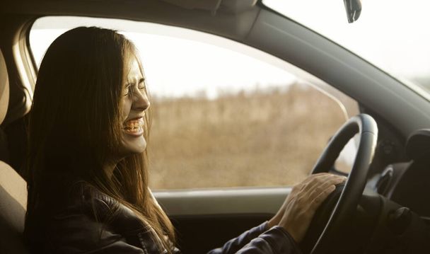 Beautiful young brunette woman sitting inside of modern car.  hispanic girl sitting on the driver's seat behind the wheel - 写真・画像