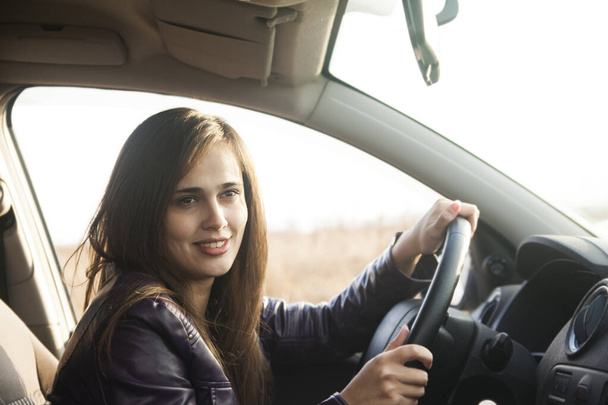 a young latino hispanic woman looking curiously ahead from the window of her  modern car. lifestyle portrait of a successful, happy girl driving. driving and car travel  - Fotó, kép