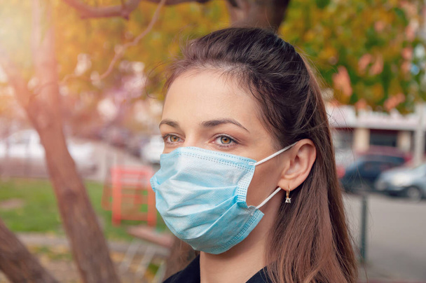 Portrait of a brunette woman with green eyes wearing a protective mask looks into the distance. - Fotoğraf, Görsel